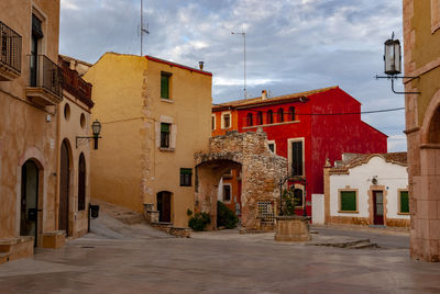 Footpath amidst buildings in town against sky