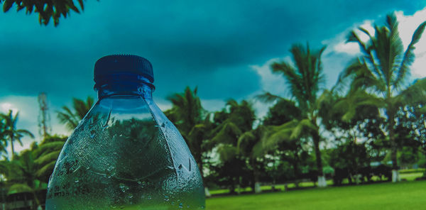 Close-up of glass bottle against blue sky