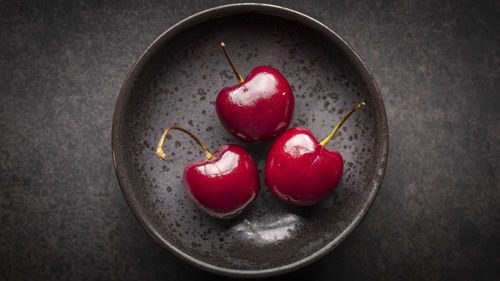 Top view, ripe red sweet cherries in rusty ceramic plate on dark tone texture background, cherry