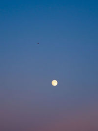 Low angle view of moon against clear blue sky