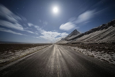 Country road amidst landscape against sky at night