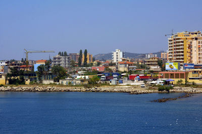 Houses by sea against clear blue sky