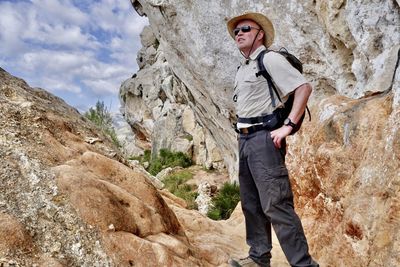 Low angle view of man standing by rock outdoors