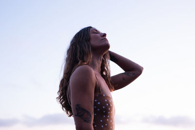 Beautiful, fit woman with tattoos on beach in tofino