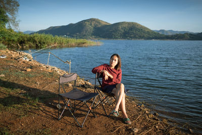 Side view of woman sitting at beach
