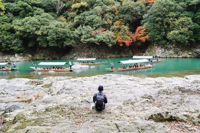 Man sitting on rock by lake in forest