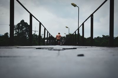 Man walking on bridge against sky