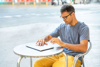 Young latin man opening his computer outside.