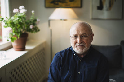 Portrait of confident senior man sitting at home