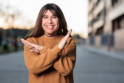 Portrait of smiling mature woman gesturing on road