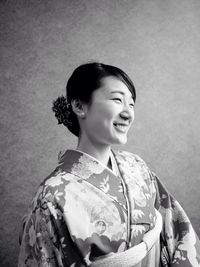 Smiling young woman wearing kimono against wall