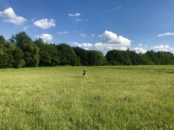 Young woman on grassy field against sky