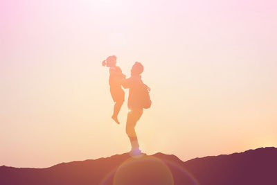 Silhouette woman standing on mountain against sky during sunset