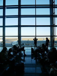 Silhouette people at airport against sky