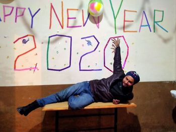 Portrait of young man lying on wall