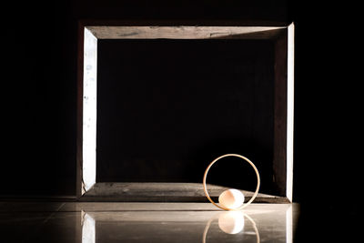 Close-up of illuminated lamp on table against black background