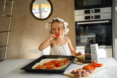 Little girl cooking pizza in the kitchen