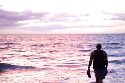 Rear view of man looking at sea against sky