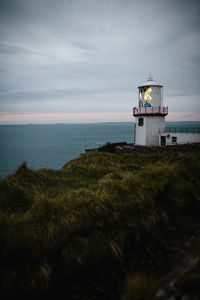 Lighthouse by sea against sky