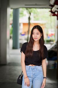 Young woman looking away while standing indoors