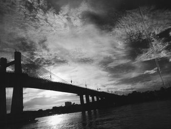 View of bridge over calm sea against cloudy sky