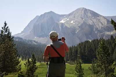 Rear view of man standing on mountain against sky