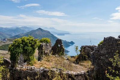 Old ruins by mountains and sea against sky