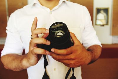 Midsection of man holding dslr camera
