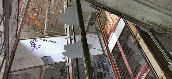 Low angle view of text hanging on wall of abandoned building