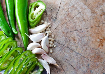 High angle view of chili peppers and garlic clove on wood