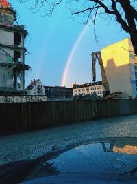 Rainbow over buildings in city against sky