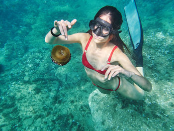 Unrecognizable young woman in diving mask swimming in deep transparent sea water and exploring jellyfish