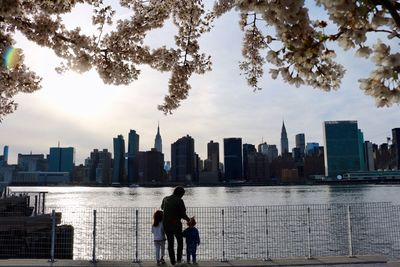 Family at riverbank against buildings in city