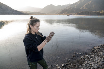 Woman putting mud on hands and face while enjoying outdoors in nature.