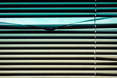 Full frame of horizontal window blinds in gradient blue green cream color a single panel creased