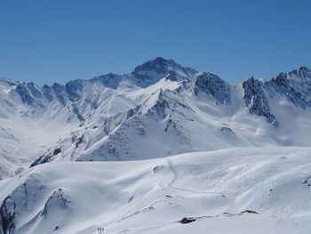 Scenic view of snowcapped mountains against clear blue sky