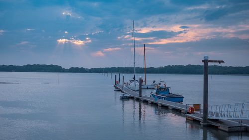 Sailboats moored in marina at sunset