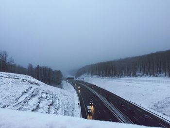 Cars on road against clear sky during winter