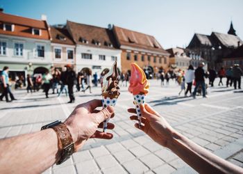 Cropped hand of couple holding ice cream cones