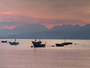 Sailboats on sea against sky during sunset