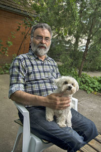 Portrait of man with dog sitting outdoors