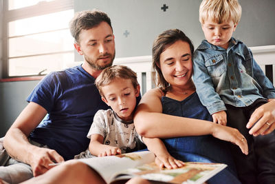 Parents and kids sitting on bed at home