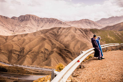 Side view of men standing against mountains