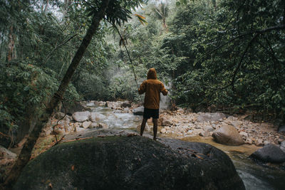 Rear view of man looking at waterfall in forest
