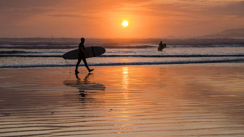 Silhouette people on beach during sunset