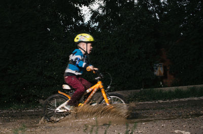 Side view of boy riding bicycle on muddy field