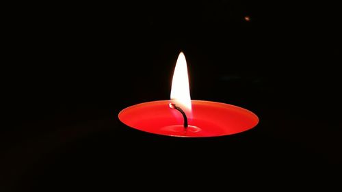 Close-up of illuminated candle against black background