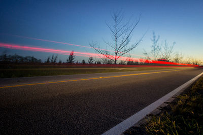 Road by bare trees against sky