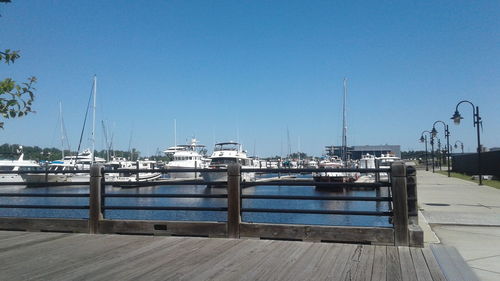 Sailboats moored at harbor against clear blue sky