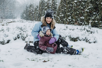 Happy family, mother and son having fun outdoors in winter snowy nature background. mom and kid